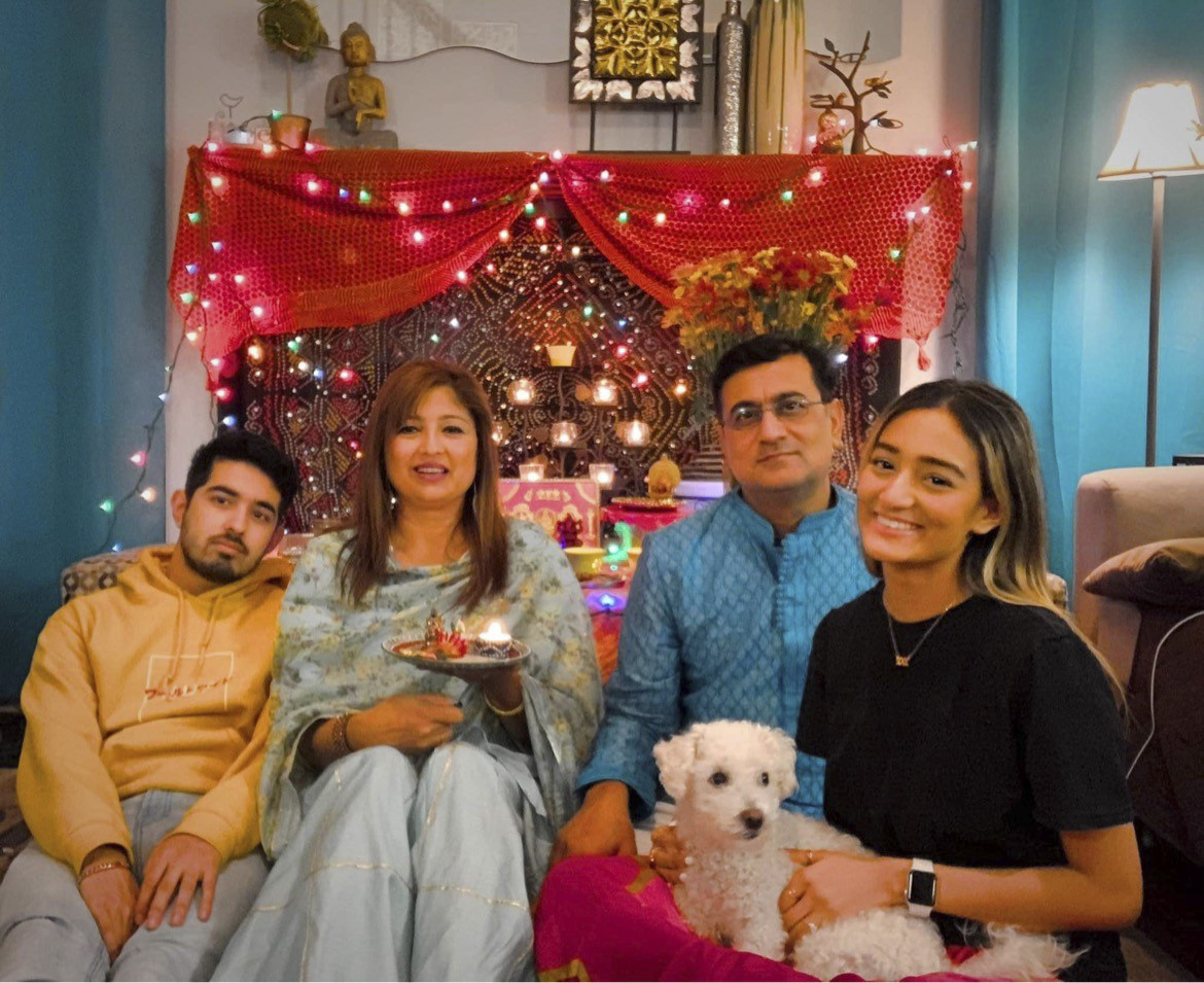Maryland Heights residents Mala, Dinesh, their two children, and their dog smile inside a bright, cheery room